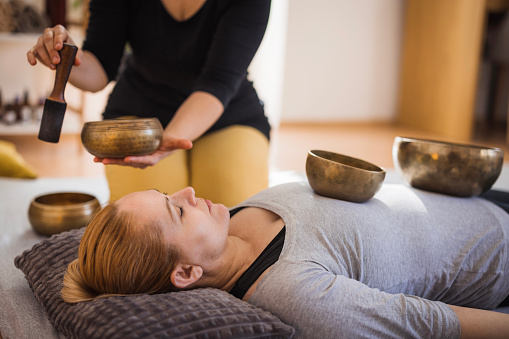 Female healer using Tibetan singing bowls during therapy session