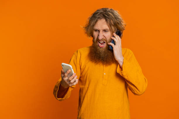 istock Irritated stressed business man talking on two mobile phones having conversation conflict quarrel 2035394663