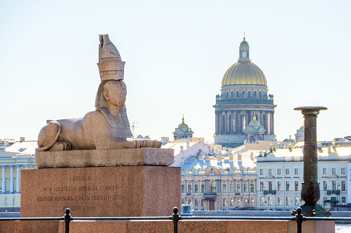 St. Petersburg, Russia - 29 September 2023: Sphinx on the University embankment and St. Isaac's Cathedral in St. Petersburg (inscription Sphinx from ancient Thebes of Egypt transported to city of Saint