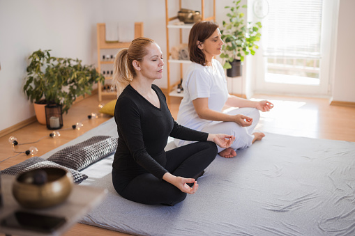 Women sitting in a lotus position and exercising yoga together