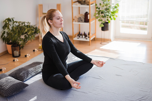 Woman sitting in yoga position making mudra and meditating