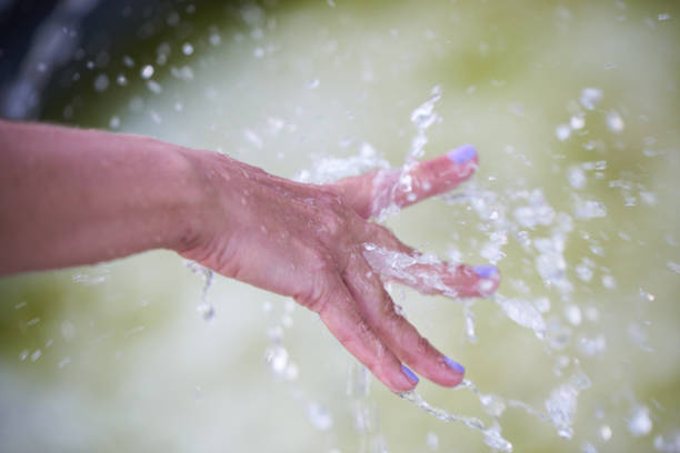 istock A woman's hand under splashes of water from a fountain 2035406431