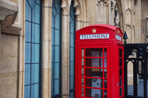 Macao, China - May 12, 2023: A red telephone booth stands in front of a building in Macau, creating a contrasting scene.