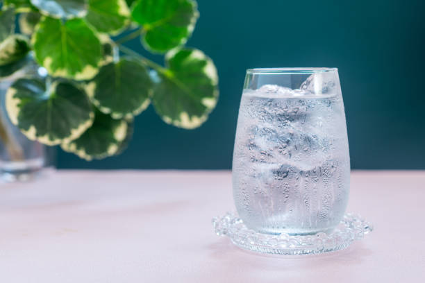 istock A glass of water with ice on pink table. 2035423087