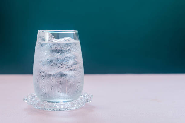 istock A glass of water with ice on pink table. 2035423092