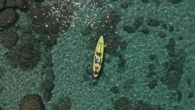 Aerial shot descending over a man sunbathing on a kayak
