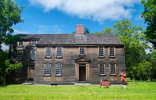 Concord, Massachusetts, August 35, 2019.  A man dressed up in a period costume playing the flute at the historic Colonel James Barrett House and Farm within the Minute man national park in Concord Massachusetts.