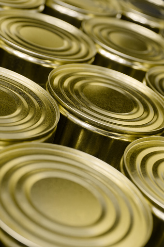 Large group of blank unlabelled round tin cans, abstract food industry background