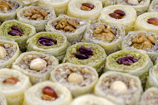 Assorted traditional Turkish dessert, baklava, with various fillings and toppings, abstract food background