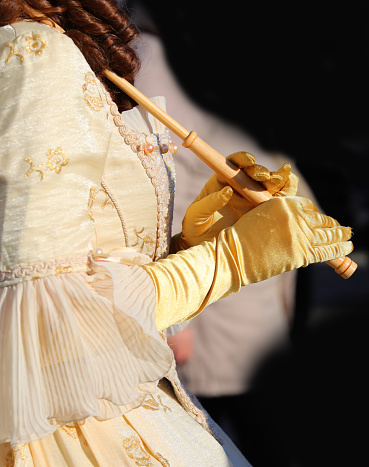 hands of girl with silky yellow gloves holding the handle of the umbrella dressed in historic nineteenth-century dress