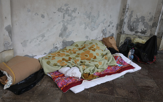 very poor homeless man sleeps under the filthy blanket in winter along the city street