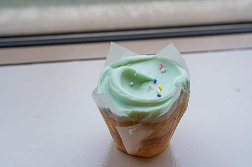Closeup fancy cupcake, green frosting over vanilla cupcake.