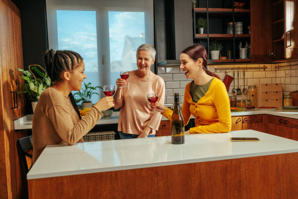istock Women smiling and drinking wine in the kitchen 2035540251