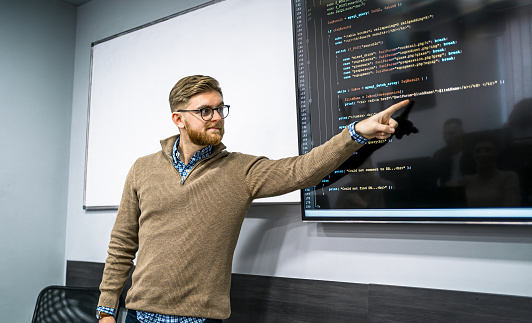 A male instructor teaching in a programming school during the class