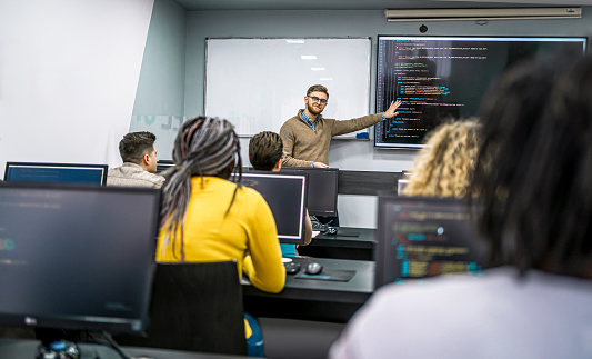 Male teacher and multi-ethnic students in programming school during the class