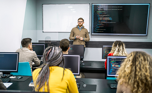 Male teacher and multi-ethnic students in programming school during the class