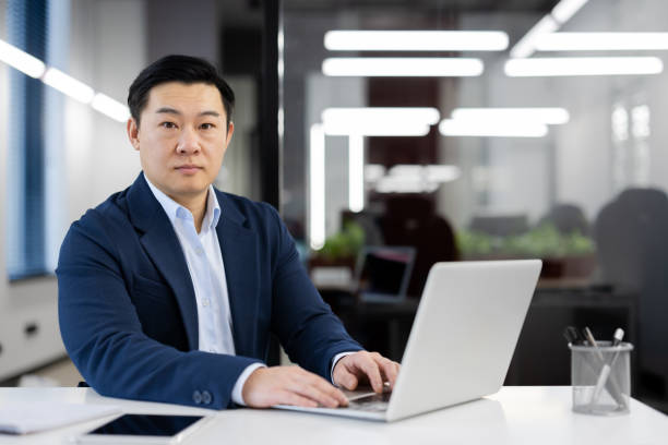 istock Confident asian businessman working on laptop at modern office desk 2035632019