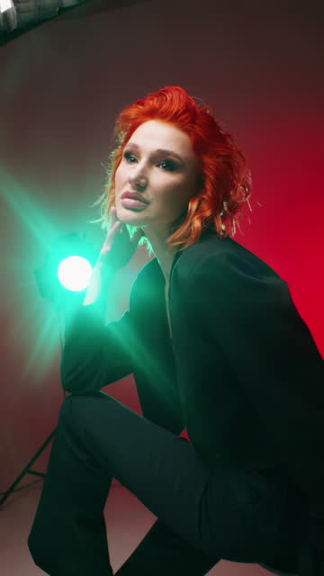 Fashion Portrait of a Red-Haired Model in Chic Black Attire Against a Red Backdrop