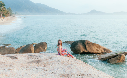 Young woman sitting on coastal rocks near the beach