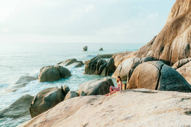 Wide angle scenic view of coastal rocks. Young woman in a serene and tranquil environment, Ko Samui, Thailand