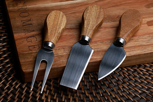 Cheese knives and fork on cutting board