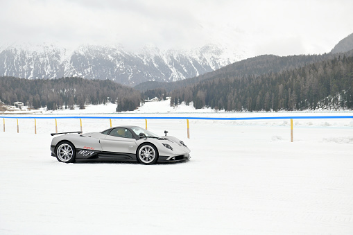 St.Moritz, Switzerland - February 22, 2024:
A vehicle of the brand, Pagani Zonda C12 (1999) He drives a few show laps on the ice on the
Lake St. Moritz. “The Ice” is an event in St. Moritz. It is an international competition of elegance. Over a hundred different luxurious and exclusive vehicles meet on the frozen lake. They do laps on the frozen lake. Unfortunately this year the event was canceled due to bad weather. Because it snowed for two days. And there is too much snow on the frozen lake.

The 40 centimeter thick layer of ice on the lake is the venue for various winter sports and events. For example, the legendary Snow Polo World Cup tournament and the legendary White Turf horse race. The photo was taken at the barrier at the edge