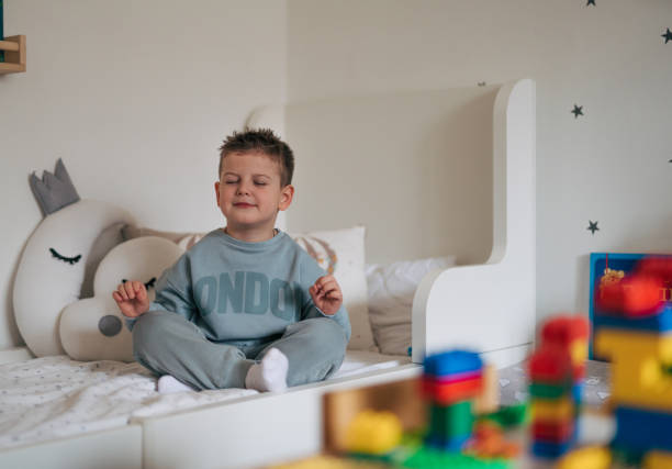 istock a little boy meditates on a bed. 2035754309