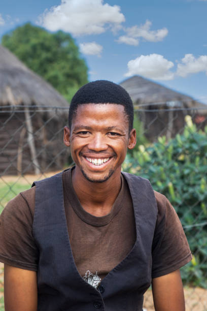 village african man standing in the yard, in the background hut with thatched roof, in south africa - africa south africa african culture plain imagens e fotografias de stock