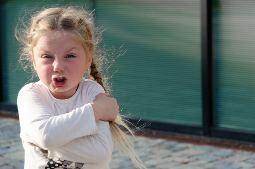 Child's emotion is anger. A four year old girl, blonde with pigtails, with a pronounced emotion of anger and aggression. Space for text.