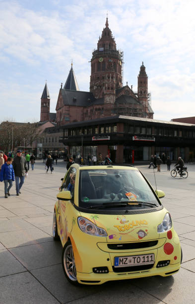 Car with Advertising  on Display at Marketplace with people and Mainz Cathedral in Mainz, Germany Mainz, Germany-March 28,2015:Yellow Car with Advertising  on Display at Marketplace with people and Mainz Cathedral church hessen religion wiesbaden stock pictures, royalty-free photos & images
