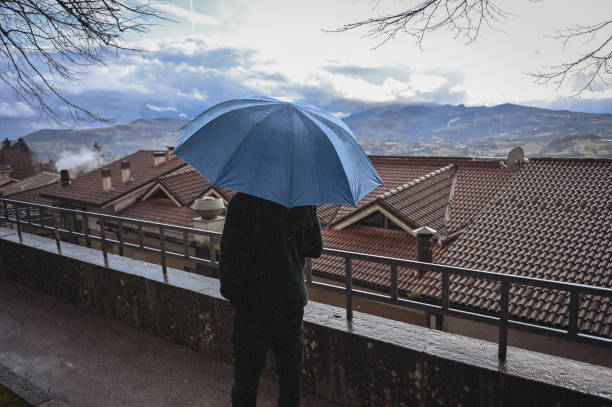 istock One man under umbrella in a city street looking at view. 2035809586