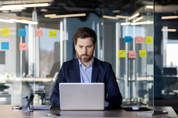 istock Serious concentrated thinking financier businessman at workplace preparing electronic financial report, mature experienced man in business suit typing laptop keyboard, reading report, inside office 2035830557
