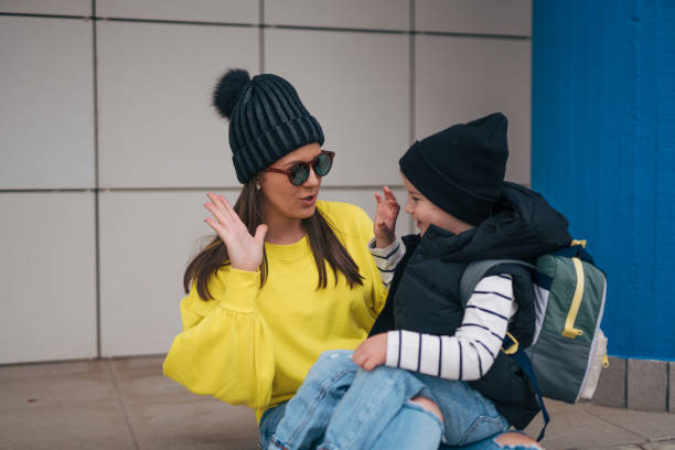 the son is sitting on his mother's lap. They spend time outside and have a great time.