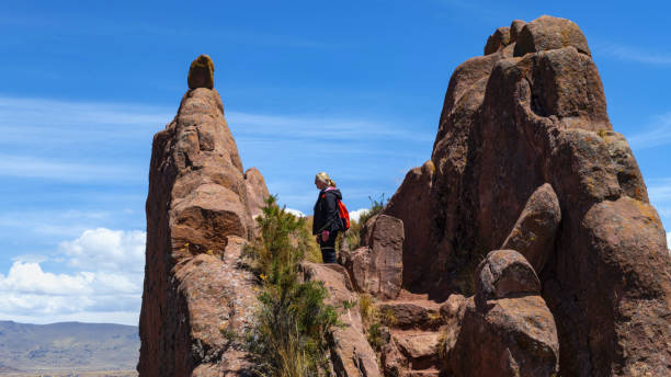 Juli, Peru, November 19, 2021: A female tourist looks from a rock in the archaeological site of Aramu Muru in Peruvian Andes which is an abandoned stone carving near Lake Titicaca. Aramu Muru is known as Gate of the Gods and is believed to be an abandoned Incan construction project.