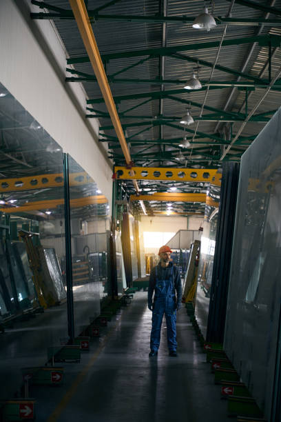 istock Man in overalls stands in a window production workshop 2035858873