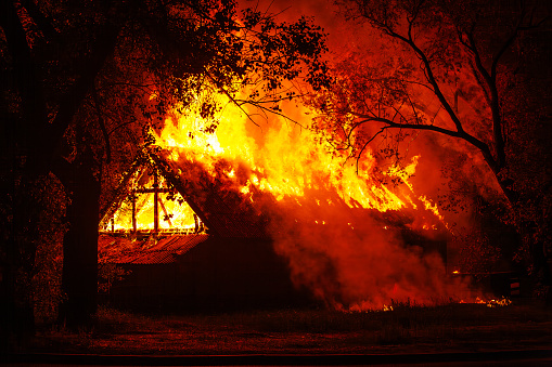 Arson or nature disaster - burning fire flame on wooden house rooft