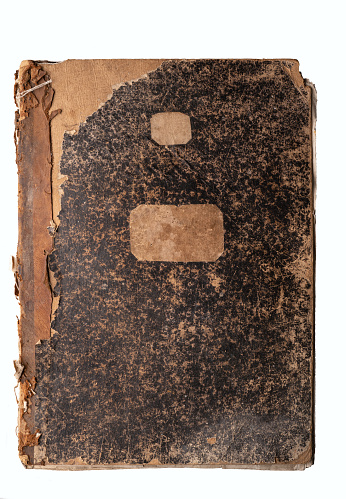 An antique music notebook with a heavily worn and partially torn black cover. There are stickers for the name. Vintage. Background.