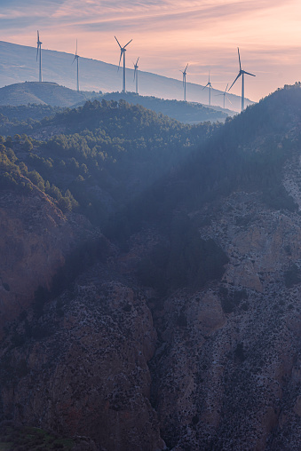 Wind turbines on the top of the mountains, with Sierra Nevada in the background at dawn.