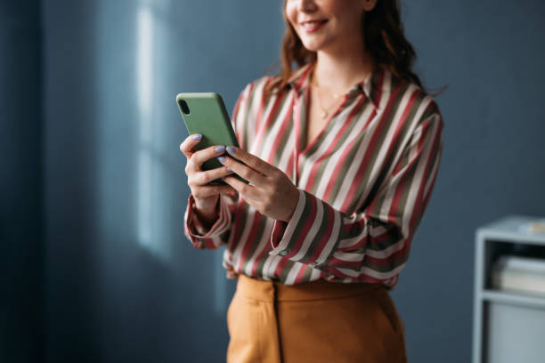 istock Smiling Woman Using Smartphone for Communication in Casual Setting 2035915067