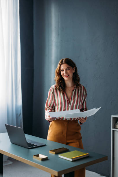Confident Businesswoman Smiling with Documents in Modern Office