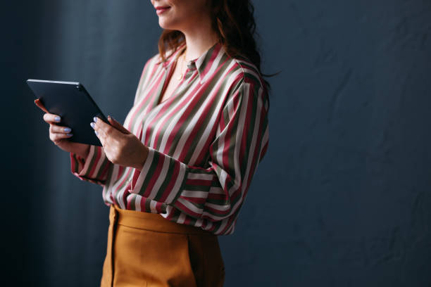 istock Professional Woman Using Tablet on Dark Background in Stylish Outfit 2035915079