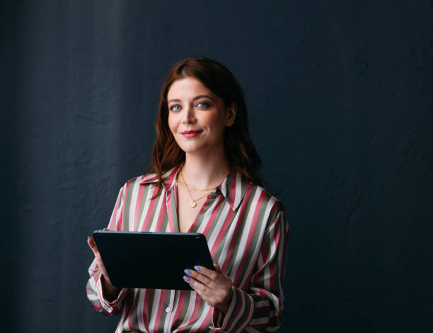 Confident Businesswoman with Tablet on Dark Background