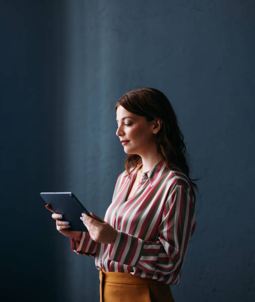 istock Professional Woman in Striped Shirt Using Digital Tablet Against Blue Background 2035915086