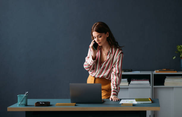 istock Professional Woman on Phone Call Using Laptop at Modern Office Desk 2035915600