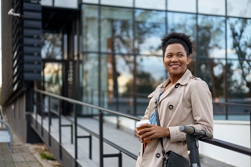 Smiling Mature African American Businesswoman With Takeaway Coffee Coffee Standing Outside Office Building