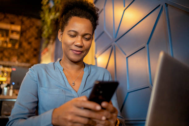 African American Female Entrepreneur Working With a Phone and Laptop in a Coffee Shop