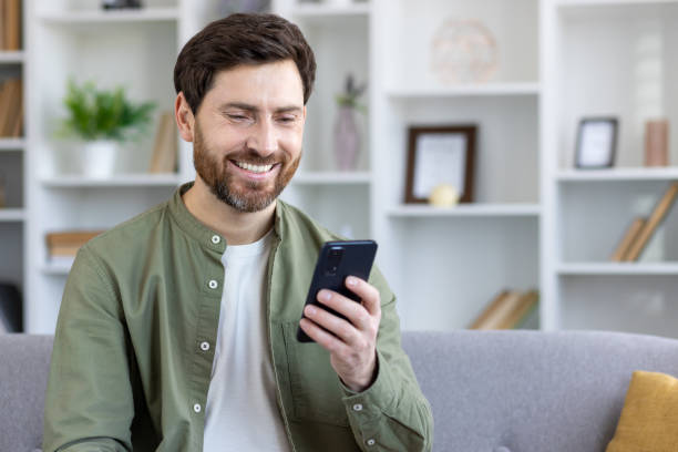 istock Satisfied mature man sitting on sofa in living room, using app on phone, freelancer holding smartphone, reading and typing text message, browsing social media 2035960157