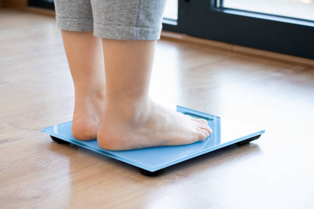 istock woman checking kilogrammes on the weight scale 2035979837