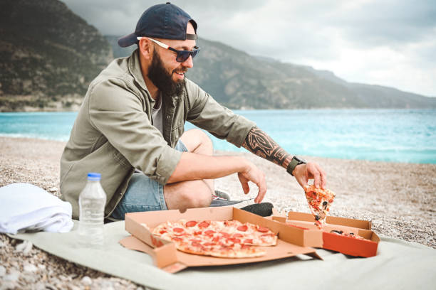 istock Man resting on the beach and eat pizza 2035986788
