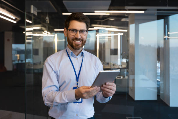 istock Portrait of mature experienced programmer system administrator, man smiling and looking at camera with tablet computer in hands, mature worker testing new software inside office at workplace 2035990427